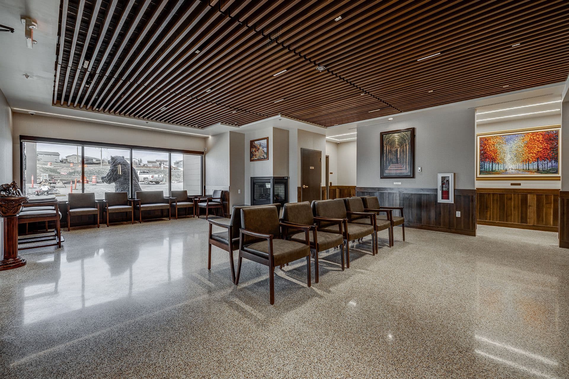 Modern waiting room with tiled floor dark wood interior brown leather chairs and big window with faux black bear
